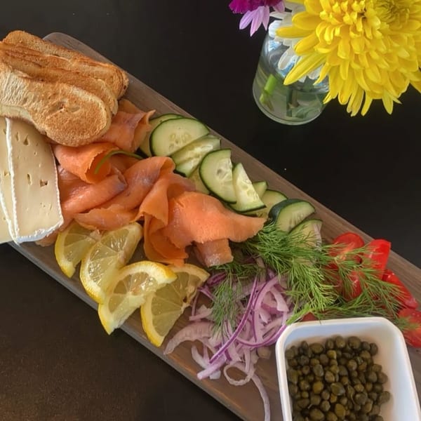 A Bruchelle's Bagel Bistro lox platter with salmon, cheese, capers, vegetables, and bread.