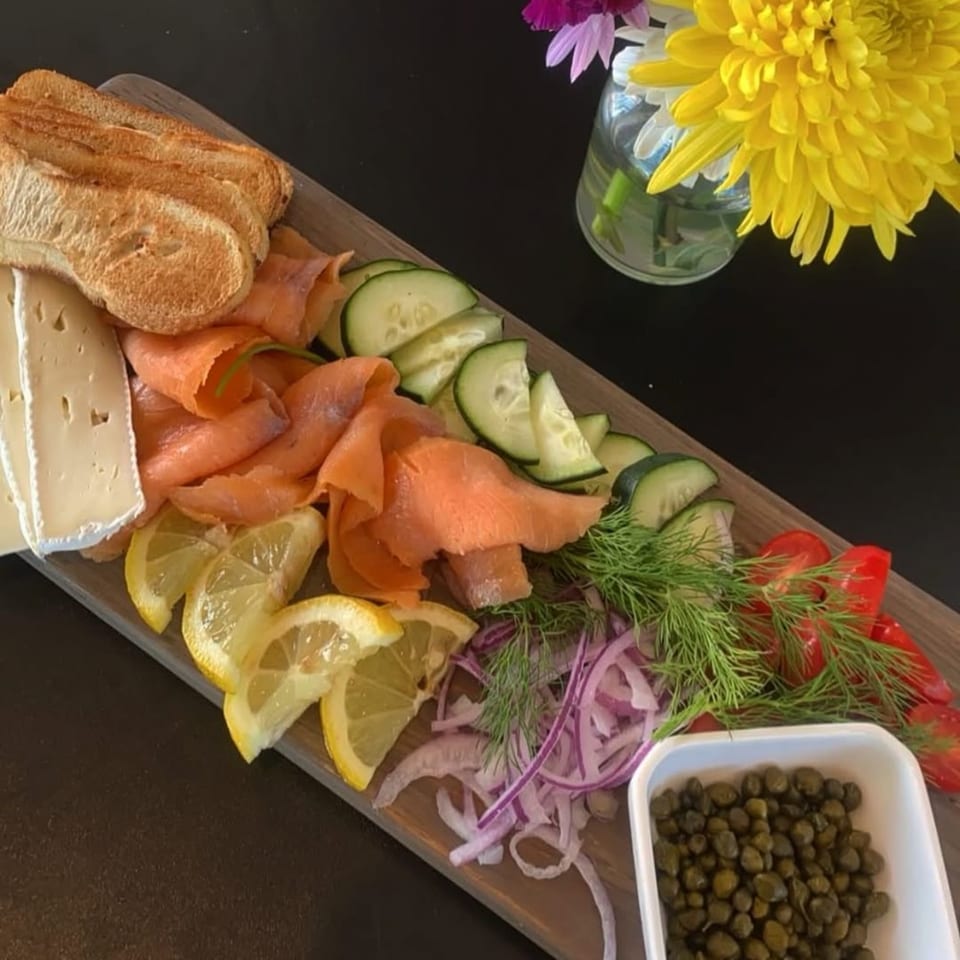 A Bruchelle's Bagel Bistro lox platter with salmon, cheese, capers, vegetables, and bread.